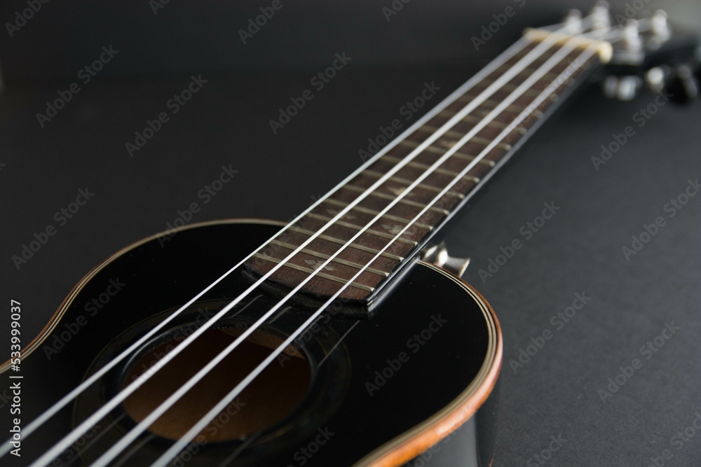 Close up ukulele isolated on dark background. Copy text. Close up ukulele isolated on dark background. Copy text.