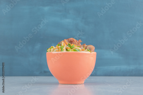 An orange bowl of delicious meat with vegetable salad