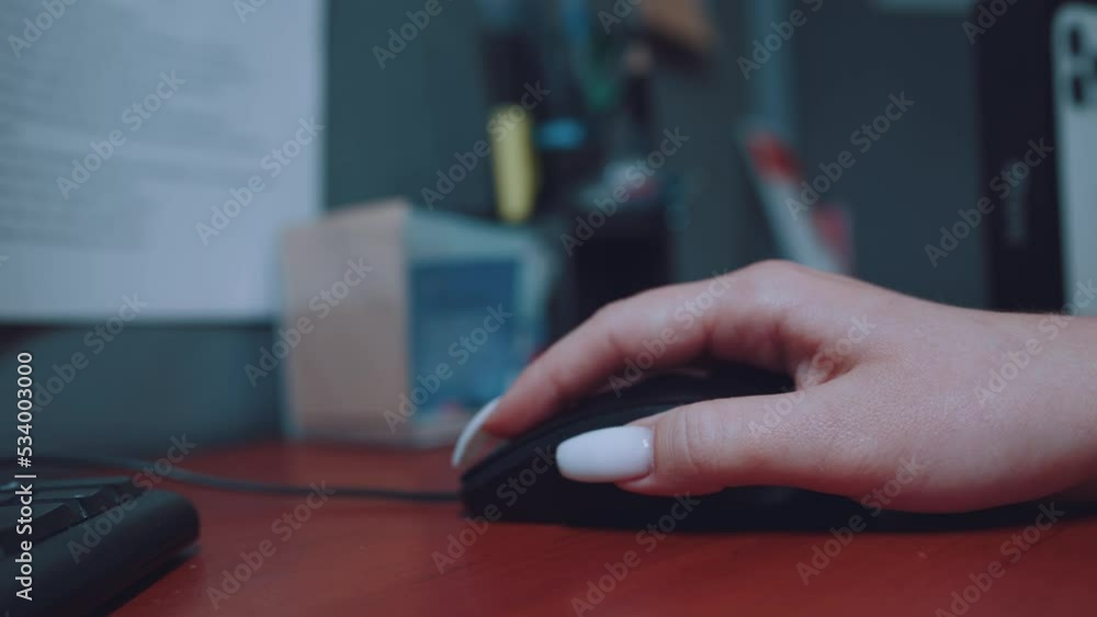 A woman's hand with a manicure moves a computer mouse and clicks on it A woman's hand with a manicure moves a computer mouse and clicks on it