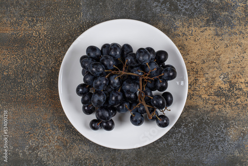 Cluster of black grapes on white plate