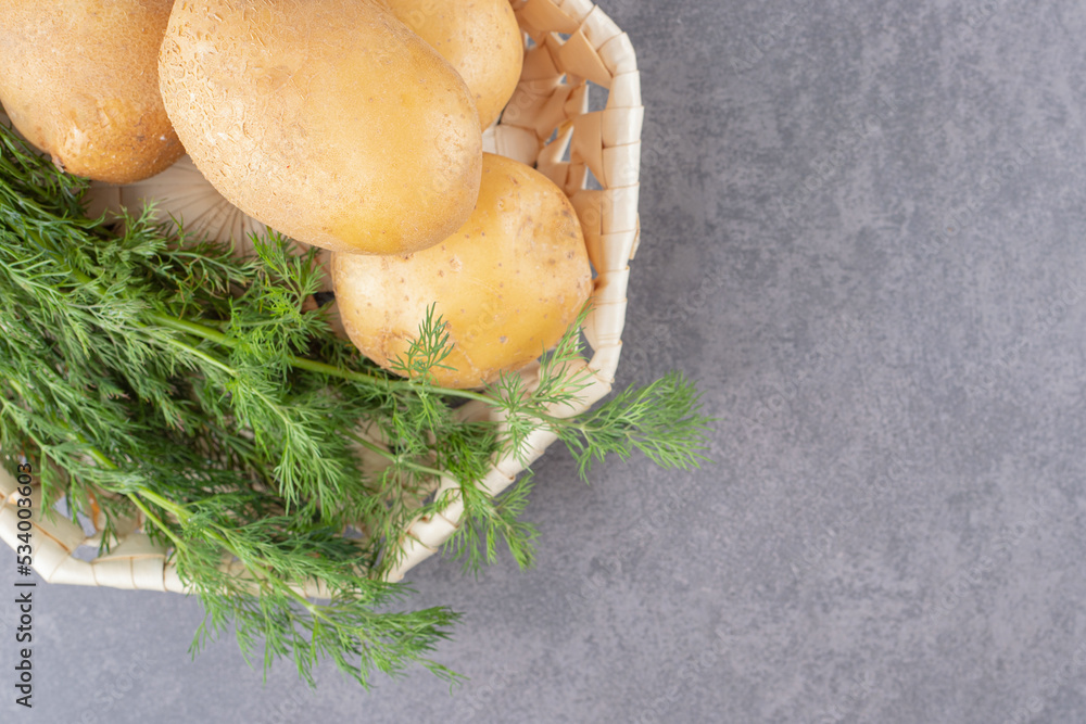 A white plate of uncooked potatoes with fresh dill A white plate of uncooked potatoes with fresh dill