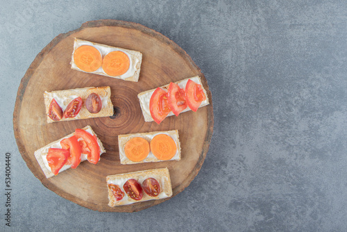 Crispy toasts with tomatoes on wooden board