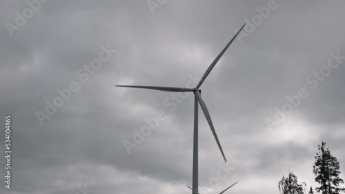 Wind turbine slowly rotating against the cloudy sky 
 photo