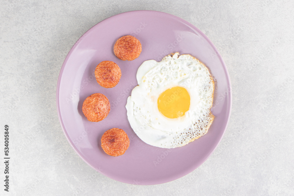 Sliced grilled sausages and fried egg on purple plate Sliced grilled sausages and fried egg on purple plate