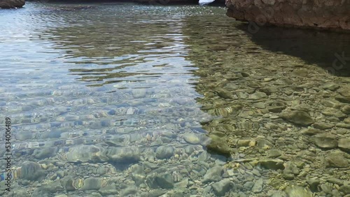 View of the rocks sticking out of the water on the Beritnica beach on the Croatian island of Pag, slow motion, with the sea and mountains in the background