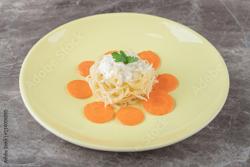 Freshly baked spaghetti with carrot on the plate , on the marble background