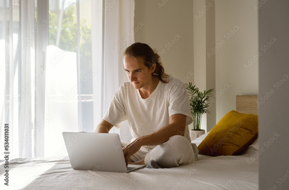 Young man with laptop on bed working from home. Young man with laptop on bed working from home.