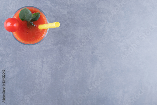 Top view. Glass of fresh tomato juice and tomatoes on a grey background