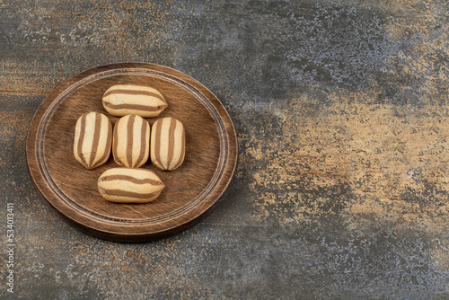 Delicious chocolate striped biscuits on wooden plate
