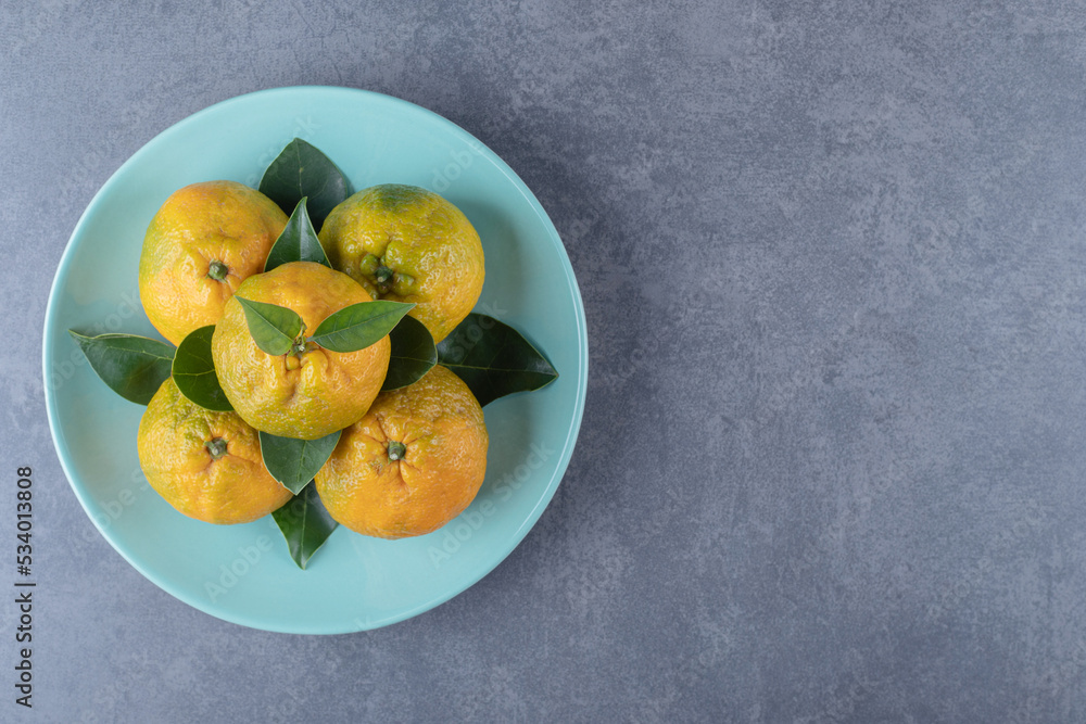 Top view of fresh organic tangerines on blue plate