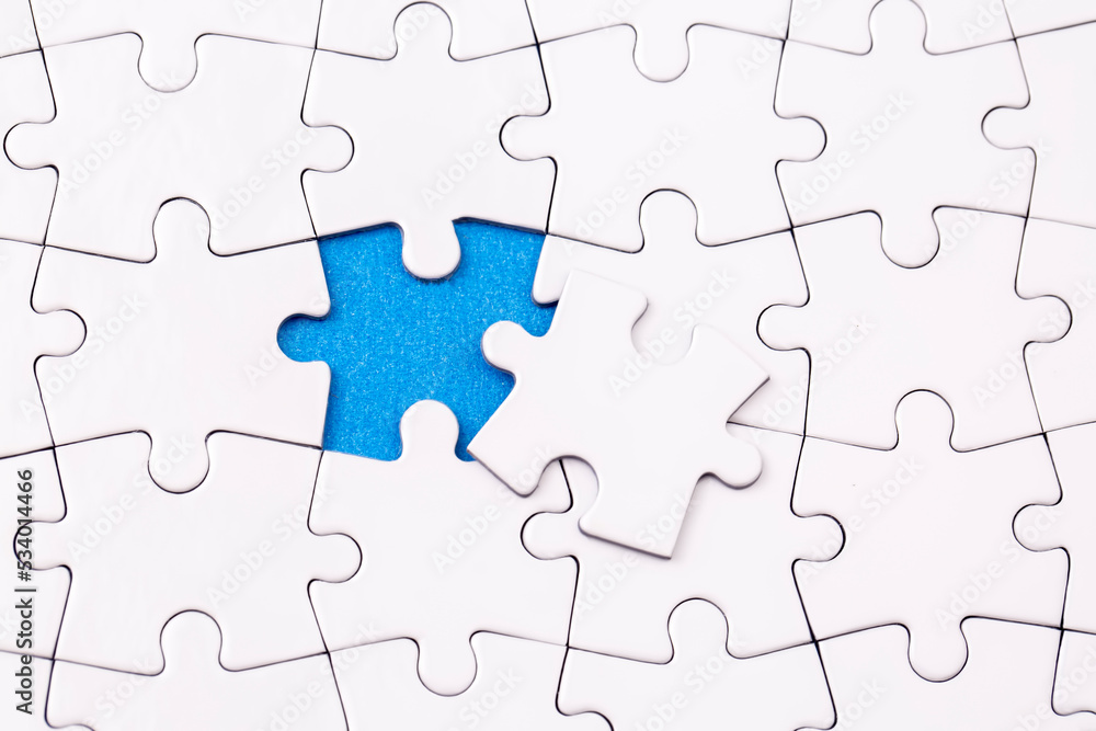 Missing jigsaw puzzle pieces. Business concept. Fragment of a folded white jigsaw puzzle and a pile of uncombed puzzle elements against Missing jigsaw puzzle pieces. Business concept. Fragment of a folded white jigsaw puzzle and a pile of uncombed puzzle elements against