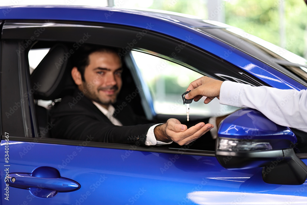 auto business, car sale, deal, gesture and people concept of dealer giving key to new owner. Closeup hand giving a car key, lease and rental concept.