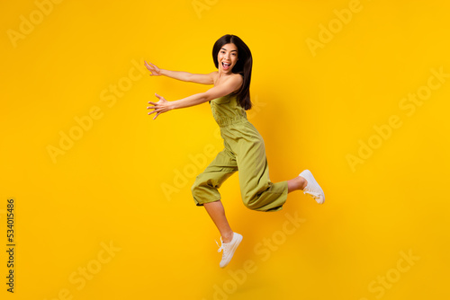 Fototapeta Naklejka Na Ścianę i Meble -  Full length photo of overjoyed excited girl jump arms catch empty space isolated on yellow color background