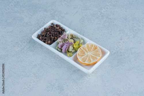 Dry sliced lemon, tea leaves and flower in the bowl, on the marble background