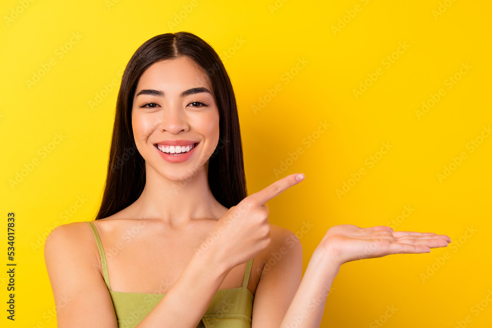 Photo of charming cute young lady wear green outfit pointing holding arm empty space isolated yellow color background Photo of charming cute young lady wear green outfit pointing holding arm empty space isolated yellow color background