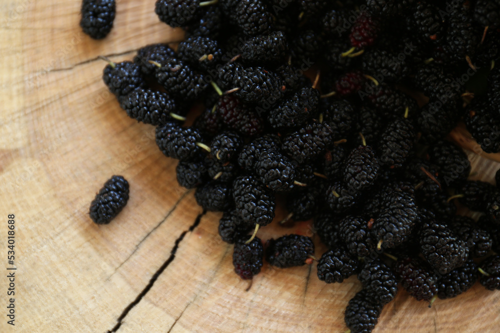 Heap of delicious ripe black mulberries on wood stump, top view Heap of delicious ripe black mulberries on wood stump, top view