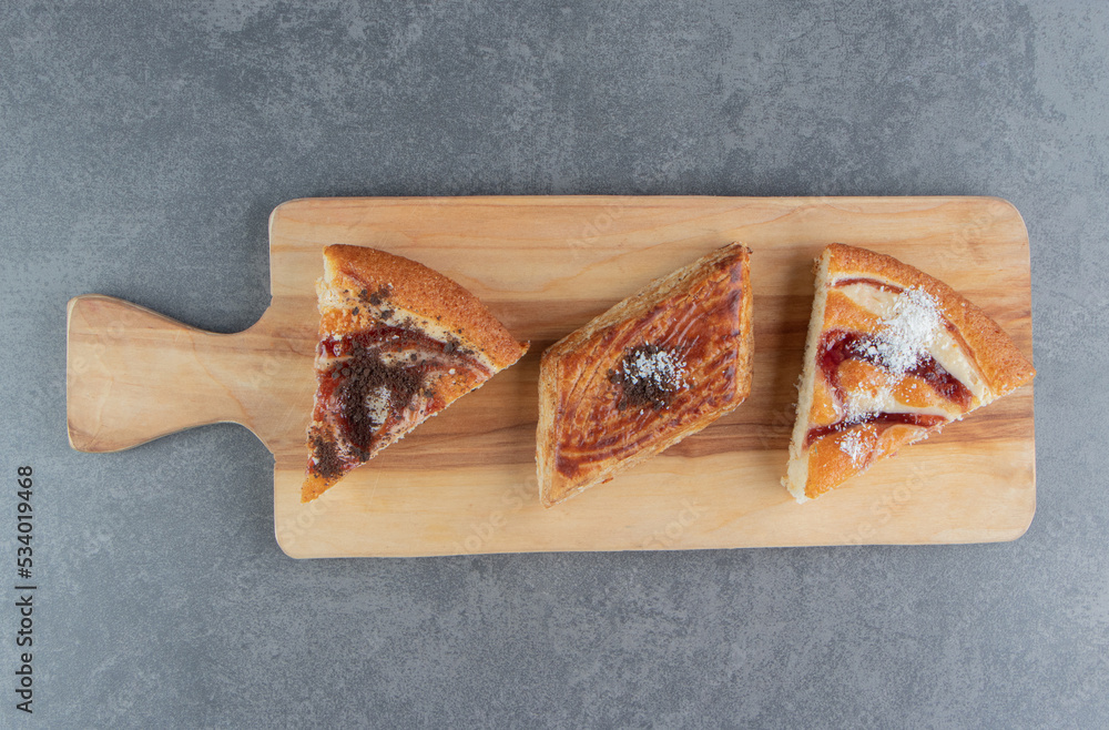 A wooden cutting board with pieces of cake A wooden cutting board with pieces of cake