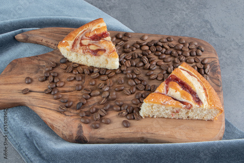 Two pieces of cakes with coffee beans on a wooden cutting board