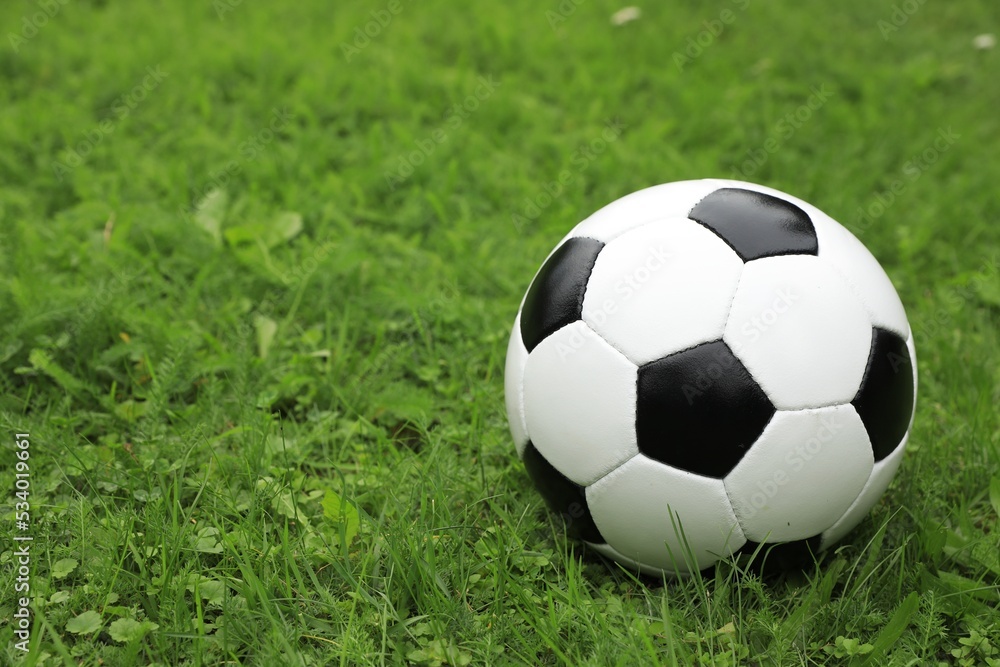 Football ball on green grass outdoors, space for text