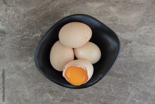 Cracked raw egg in black bowl