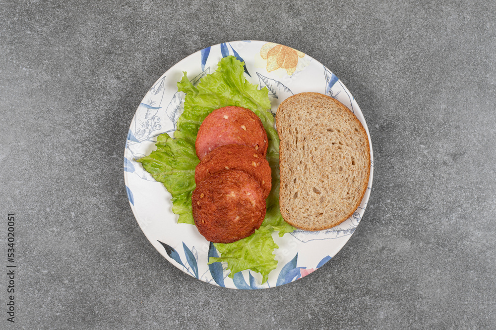 Rye bread slice and sausages on colorful plate Rye bread slice and sausages on colorful plate