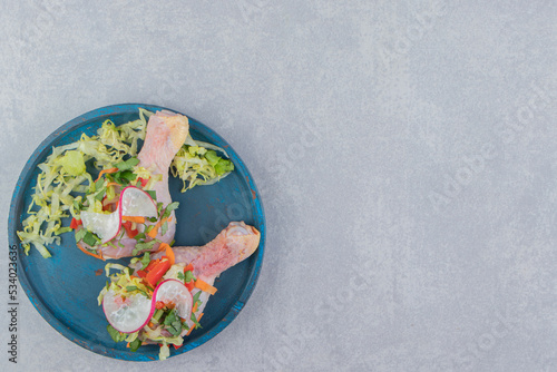 Delectable greens and raw meat in the wooden plate , on the blue background