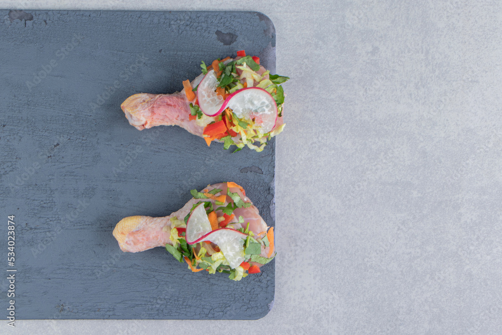 Raw marinated chicken drumsticks on the board , on the marble background