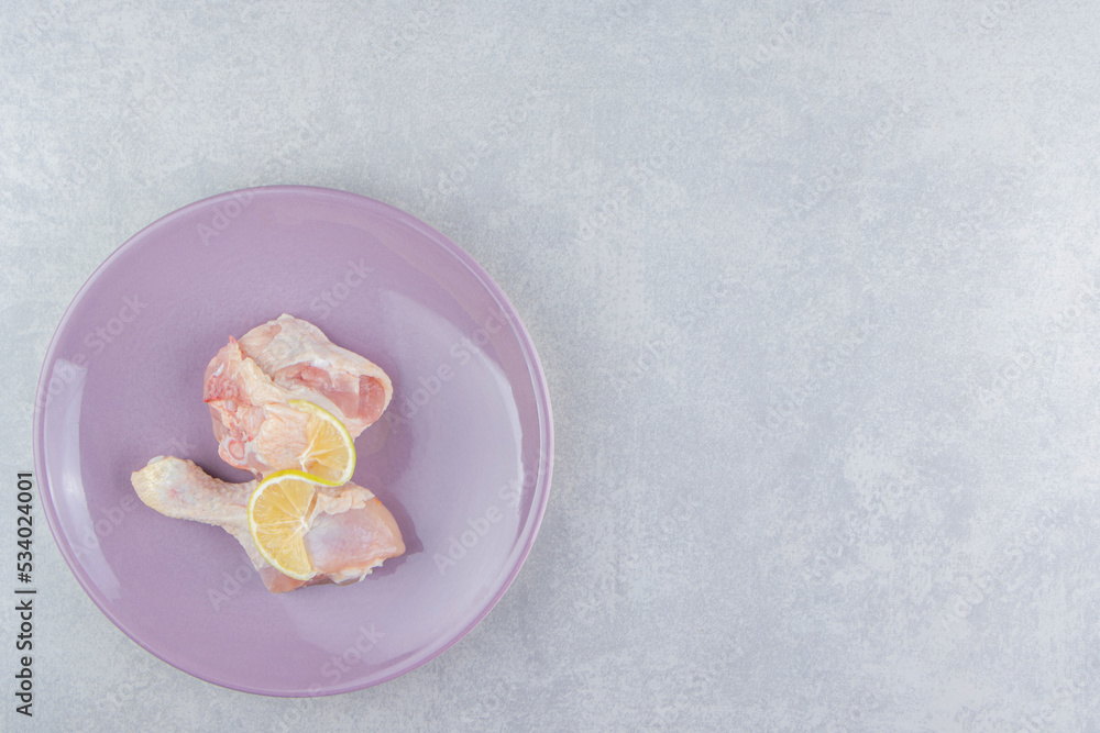 Lemon and chicken meat in the plate, on the marble background Lemon and chicken meat in the plate, on the marble background