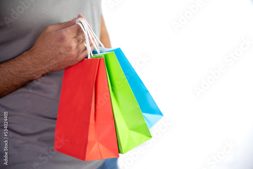 close-up of unrecognizable young man holding some colorful bags - concept shopping, black friday, sales, christmas