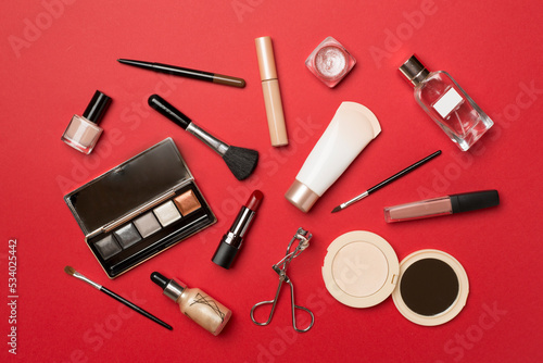 Different makeup products on color background, top view