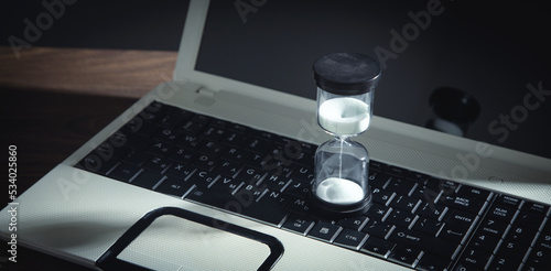 Hourglass on the laptop keyboard. Time management. Business