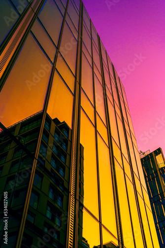 Yellow and pink abstract building background with lines. Modern office building in the evening. Facade mirror		