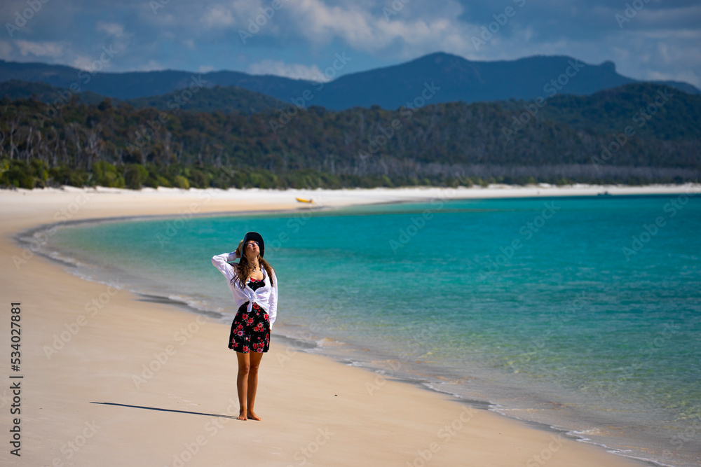 beautiful girl stands on the sand on paradise beach, beach with white sand and turquoise water, whitehaven beach on whitsunday island in australia