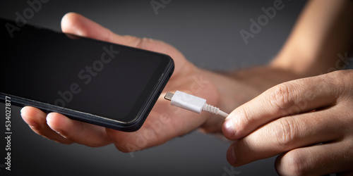 Fototapeta Naklejka Na Ścianę i Meble -  Man connecting charger cable to mobile phone.