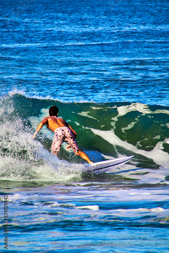 Photography man surfing riding a wave in blue sea in zicatela, puerto escondido oaxaca
