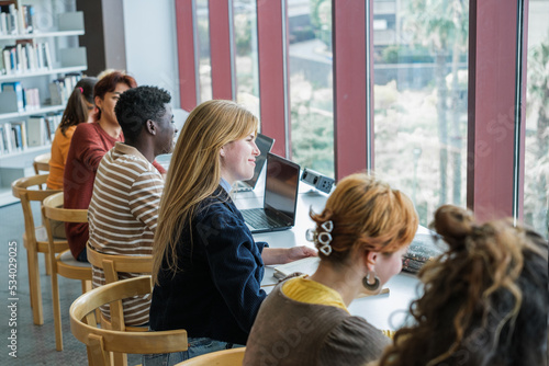 College students studying together in a brightly lit library with a large window