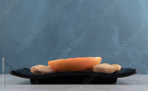 Grapefruit and almonds on the board, on the marble background