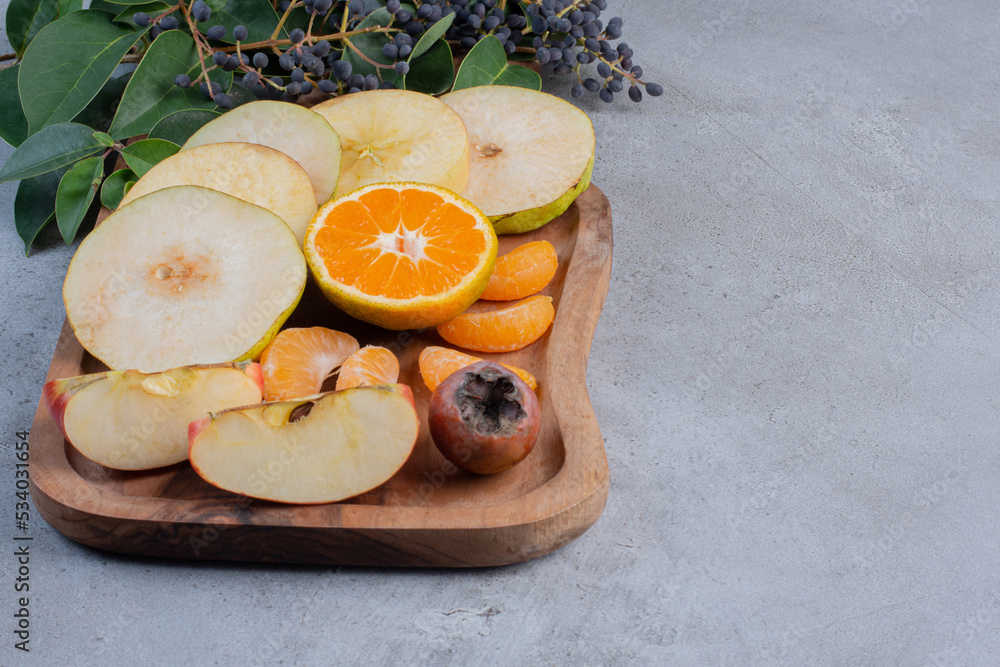 Sliced fruits bundled on a wooden board on marble background Sliced fruits bundled on a wooden board on marble background