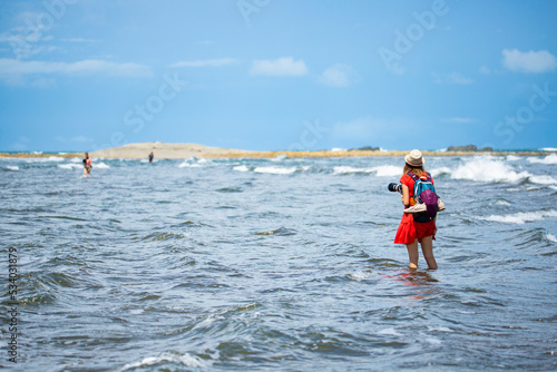 backpacker girl in red dress walks by water towards island, marino ballena national park in costa rica © Jakub