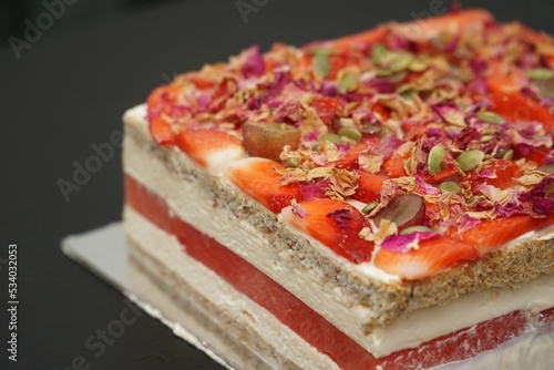 Closeup shot of a gourmet delicious cake with a layer of strawberries and floral decorations