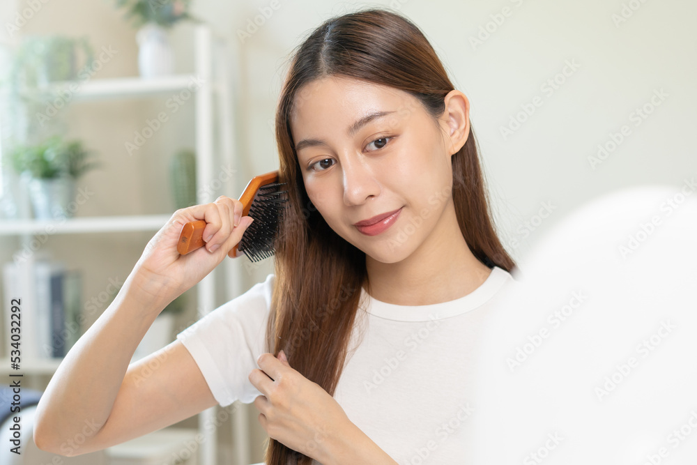 Health hair care, beauty makeup asian woman, girl holding hairbrush and brushing, combing her long straight hair looking at reflection in mirror in morning routine after salon treatment, hairstyle. Health hair care, beauty makeup asian woman, girl holding hairbrush and brushing, combing her long straight hair looking at reflection in mirror in morning routine after salon treatment, hairstyle.