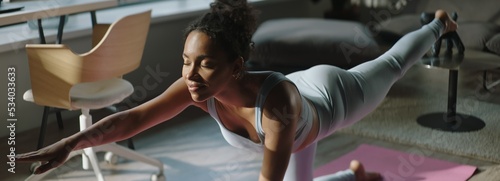 HANDHELD Young African American sporty young woman using online fitness training application to get the exercise plan during yoga workout. Shot with 2x anamorphic lens