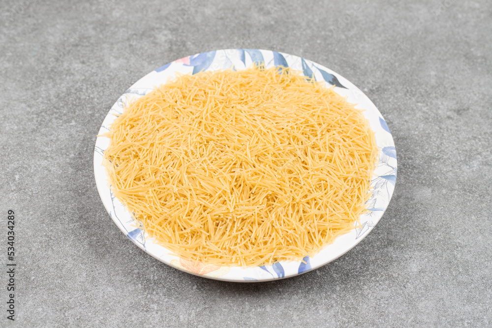 Pile of uncooked macaroni on colorful plate Pile of uncooked macaroni on colorful plate