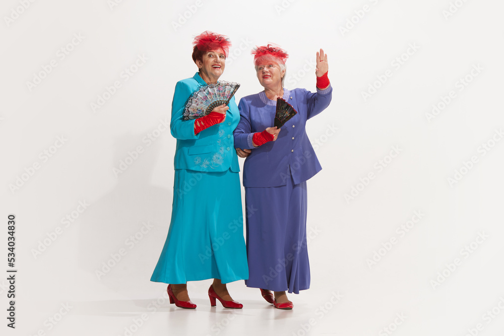 Theater-goers. Two elegant senior women in retro style autumn clothes isolated on white background. Concept of beauty, old generation, 60s, 70s fashion style Theater-goers. Two elegant senior women in retro style autumn clothes isolated on white background. Concept of beauty, old generation, 60s, 70s fashion style