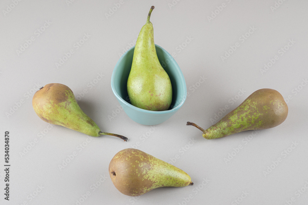 Juicy pears in and next to a tiny bowl on marble background Juicy pears in and next to a tiny bowl on marble background