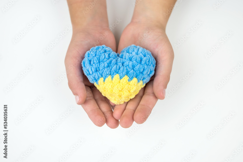 High angle view of children's hands holding a heart painted in the Ukrainian flag, hearts in hands on a white background. Patriotic concept. High angle view of children's hands holding a heart painted in the Ukrainian flag, hearts in hands on a white background. Patriotic concept.