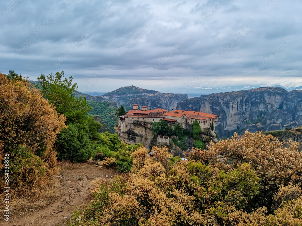 Obraz premium Scenic view of Holy Monastery of Varlaam on cloudy foggy day, Kalambaka, Meteora, Thessaly, Greece, Europe. Rock formations overgrown with green moss creating moody atmosphere. UNESCO World Heritage