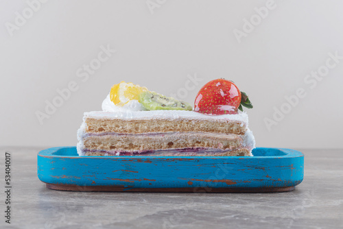 Small cake slice with fruit topping on a platter on marble background