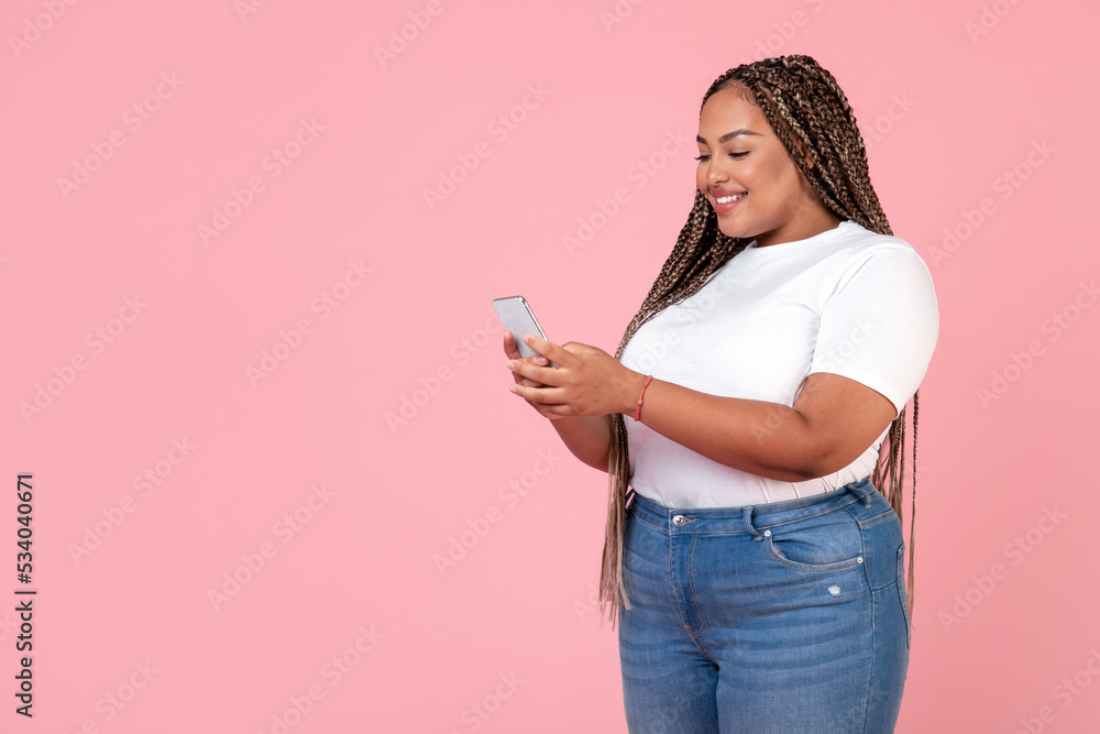 Side View Of Black Oversized Woman Using Smartphone, Pink Background Side View Of Black Oversized Woman Using Smartphone, Pink Background