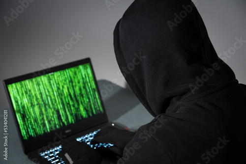 Hacker / Krimineller vor Laptop / Notebook mit schwarzem Kapuzenpullover	